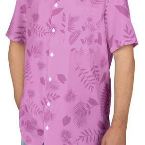 May include: A short-sleeved, button-down shirt in a light purple hue, adorned with a repeating pattern of darker purple tropical leaves and foliage. The shirt features a classic collar, a chest pocket, and white buttons.