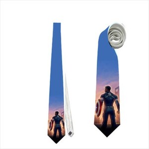 May include: Blue necktie featuring a Captain America design. The tie shows Captain America holding his shield against a sunset backdrop. The tie is blue with a white underside and a pointed tip.