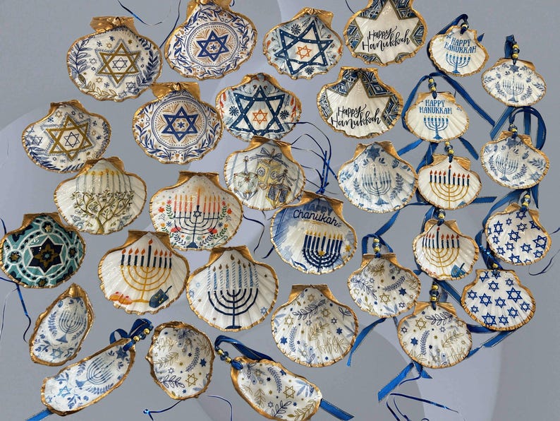 May include: A collection of hand-painted seashell ornaments with gold trim, featuring Jewish symbols like the Star of David and menorahs. Some shells have "Happy Hanukkah" text. Blue ribbons are attached for hanging.