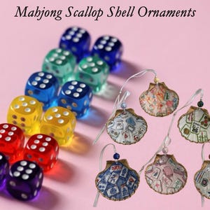 May include: A collection of colorful dice and six seashell ornaments. The dice are in various colors, including blue, green, yellow, red, and purple. The seashell ornaments have Mahjong-themed designs and are strung on a wire.