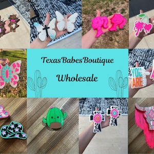 May include: Assortment of colorful, handmade, felt car air fresheners.  Designs include butterflies, cows, cacti, crosses, cherries, hats, and a bull skull.  The text "Texas Babes Boutique Wholesale" is displayed in the center of the image.
