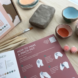 May include: A craft kit for making pinch pots with clay, tools, paint, and instructions. The kit includes a block of clay, wooden tools, small paint pots, and a booklet with instructions on how to make a pinch pot.