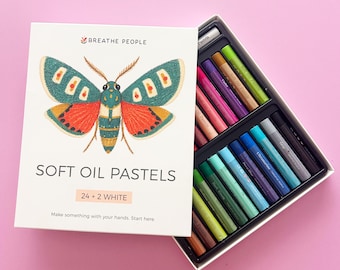 May include: A set of 26 soft oil pastels in a white box featuring a moth illustration and the text BREATHE PEOPLE SOFT OIL PASTELS 24 + 2 WHITE. The box is open, revealing rows of cylindrical pastels in various colors including green, blue, and purple.