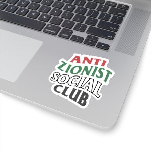May include: A sticker with the text "ANTI ZIONIST SOCIAL CLUB" in red, green, and black letters on a white background.