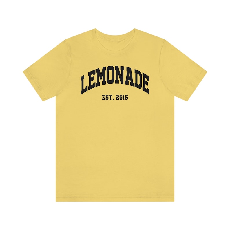 以下が含まれることがあります： レモンイエローの半袖Tシャツに、黒い文字で「LEMONADE EST. 2016」と書いてあります。