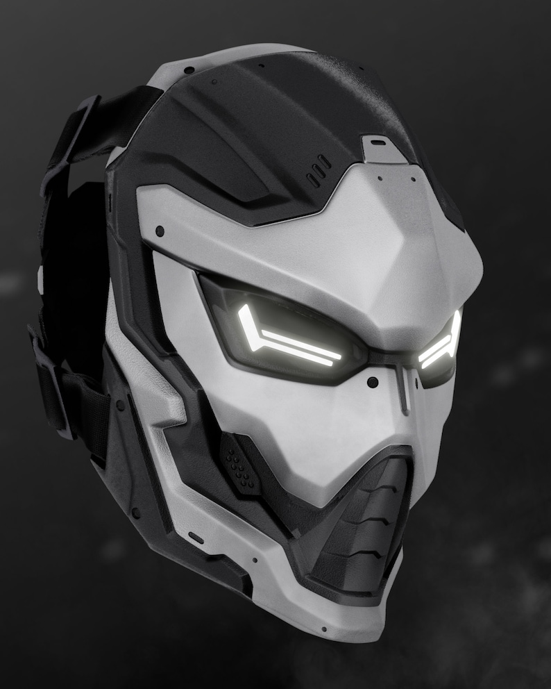 May include: A futuristic, white and black helmet with a visor and a black strap. The helmet has a geometric design and a series of small, round holes on the side.