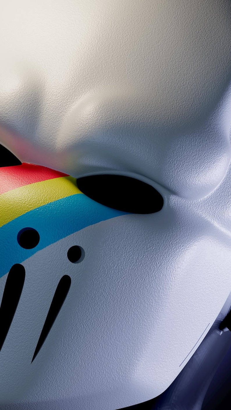 K&ouml;nnte beinhalten: Nahaufnahme einer wei&szlig;en Maske mit strukturierter Oberfl&auml;che. Die Maske hat ein Regenbogenstreifen-Design in Rot, Gelb und Blau. Die Maske hat zwei Augenl&ouml;cher und mehrere schwarze Ausschnitte.