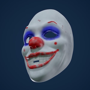 Könnte beinhalten: Eine weiße Clownsmaske mit einer roten Nase, blauen Augen und einem roten Lächeln. Die Maske hat ein paar rote Farbspritzer.