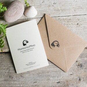 Pu&ograve; includere: Un biglietto bianco con un'illustrazione in bianco e nero di un puffin e il testo "MisprintedMind" e "www.misprintedmind.com". Il biglietto &egrave; su una superficie di legno con una busta marrone accanto.