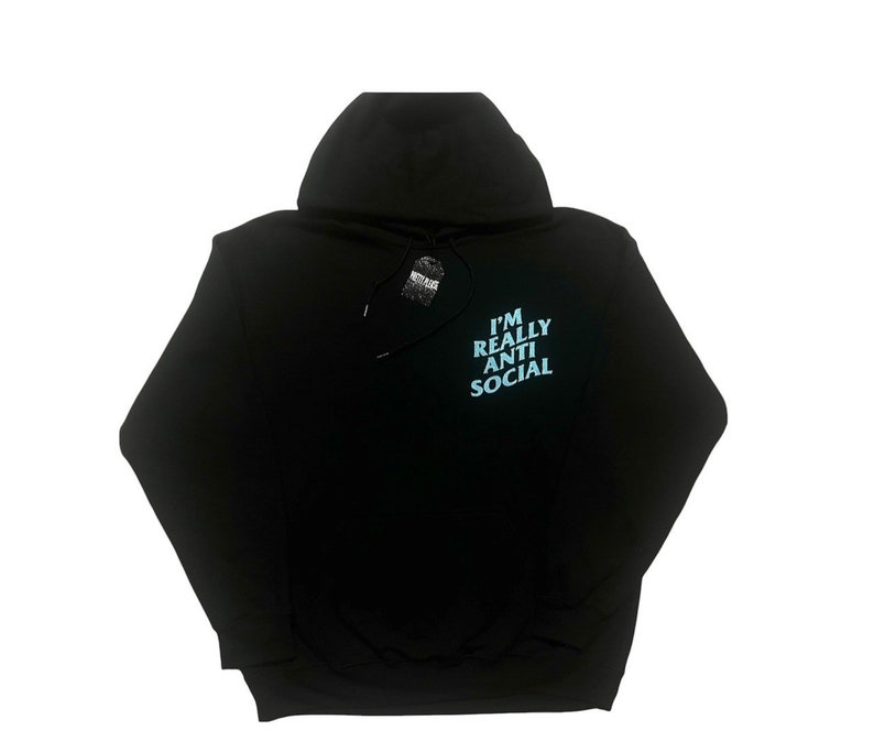 Puede incluir: Sudadera con capucha negra con el texto "I'M REALLY ANTI SOCIAL" en azul claro en la espalda. La sudadera tiene una capucha con cord&oacute;n y una etiqueta adjunta. La prenda est&aacute; hecha de un material suave.