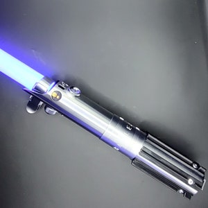 May include: A silver and black lightsaber with a blue blade. The lightsaber has a textured silver handle and a black grip.