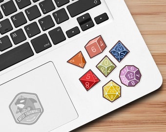May include: A set of seven colorful dice stickers featuring different numbers and shapes. The stickers are placed on a laptop computer.