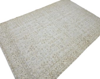 Könnte beinhalten: Ein rechteckiger, cremefarbener Teppich mit einem aufwendigen Blumenmuster. Der Teppich hat einen detaillierten Rand mit sich wiederholenden Blumen- und geometrischen Designs. Die Farbpalette ist neutral, mit subtilen Tonvariationen, die eine Vintage-Ästhetik erzeugen.