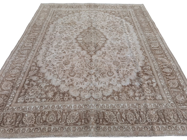 Peut inclure: Un tapis vintage de couleur beige clair et cr&egrave;me. Le tapis pr&eacute;sente un motif floral avec un m&eacute;daillon central. Le tapis a un aspect us&eacute; et d&eacute;lav&eacute;, ce qui lui donne un aspect vintage.