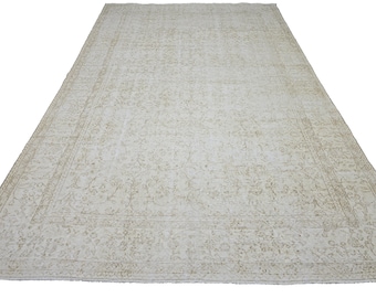 Könnte beinhalten: Ein großer, rechteckiger Teppich mit einem aufwendigen Blumenmuster in Creme- und hellgrünen Farbtönen. Der Teppich hat einen detaillierten Rand und einen Used-Look, geeignet für Wohn- oder Schlafzimmer.