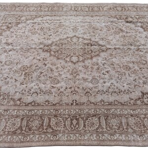 Peut inclure: Un tapis vintage avec un fond brun clair et un motif floral d&eacute;taill&eacute; en brun fonc&eacute;. Le tapis a un m&eacute;daillon central avec un motif r&eacute;p&eacute;titif de fleurs et de feuilles.