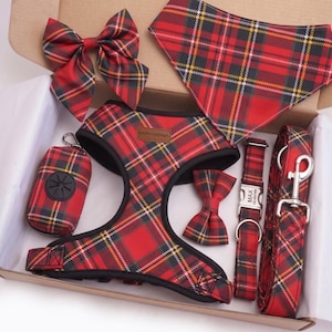 May include: A pet accessory set featuring a red, black, and yellow plaid pattern. The set includes a harness with a HappyFurPaws label, a triangular bandana, a large bow, a small bow, a waste bag dispenser, a collar with a tag reading MAX, and a leash.