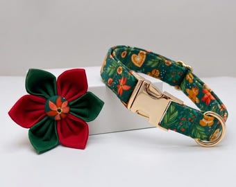 May include: A pet collar with a dark green fabric featuring a pattern of gingerbread cookies, pine branches, and berries, finished with a gold-toned metal buckle and D-ring, accompanied by a matching fabric flower accessory in red and dark green.