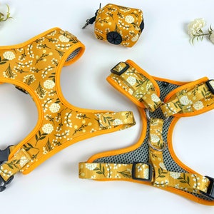 May include: Two yellow dog harnesses with a white floral pattern. The harnesses have black buckles and a silver ring.