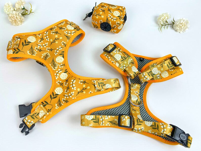 May include: Two yellow dog harnesses with a white floral pattern. The harnesses have black buckles and a silver ring.