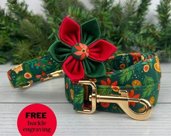 May include: A festive dog collar and leash set with a Christmas theme. The dark green fabric features a pattern of gingerbread men, oranges, and floral accents. A large red and green flower adorns the collar. Gold-colored hardware completes the set.