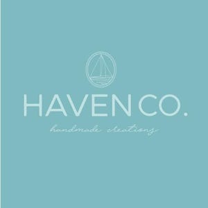 Puede incluir: Un fondo turquesa con las palabras "HAVEN CO." en una fuente sans-serif. Encima del texto hay un emblema circular con una ilustración de un velero. Debajo del texto está la frase "handmade creations" en una fuente cursiva.