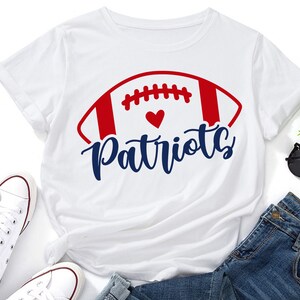 May include: White t-shirt with a red, white, and blue football graphic and the text "Patriots" in blue. A small red heart is inside the football graphic.