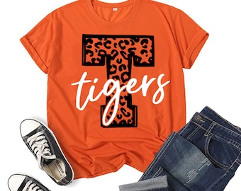 May include: Orange short-sleeved t-shirt with a black leopard print letter "T" and the word "tigers" in white text.