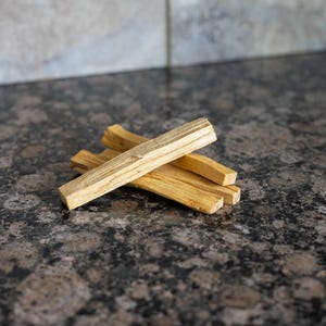 May include: Four wooden sticks bundled together. The sticks are light brown and have a rough texture.