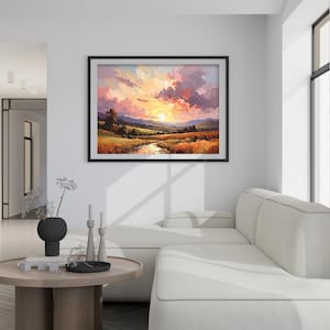 May include: A framed landscape painting depicts a sunset over a valley with a river. The artwork features vibrant colors, including orange, yellow, pink, and purple, creating a warm and inviting scene. The painting is displayed above a white sofa.