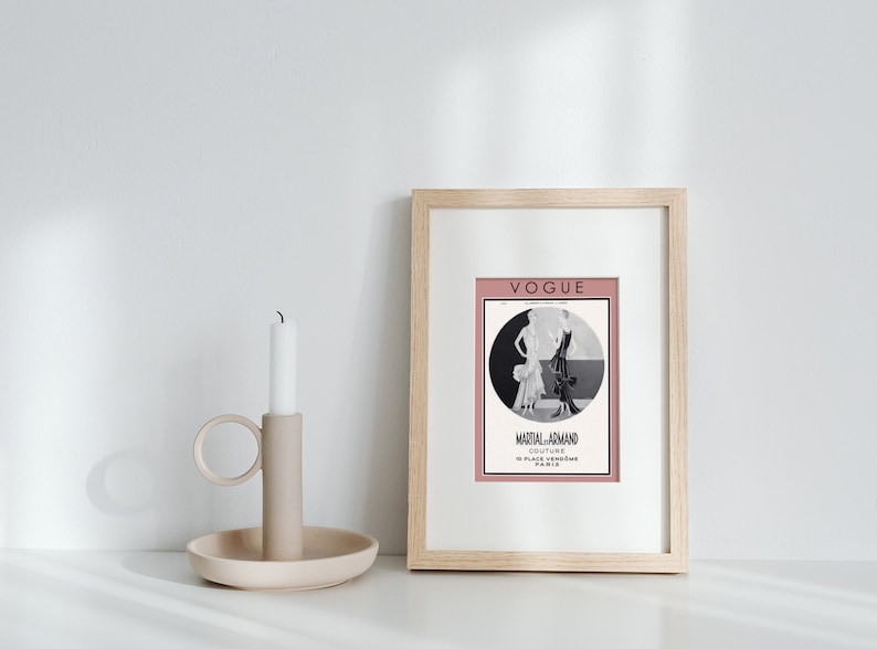 Może przedstawiać: Wydruk w ramie vintage okładki magazynu Vogue z czarno-białą ilustracją dw&oacute;ch kobiet w sukienkach. Okładka jest r&oacute;żowa z tekstem "Vogue" i "Martial-Armand Couture 10 Place Vendome Paris" w kolorze czarnym.