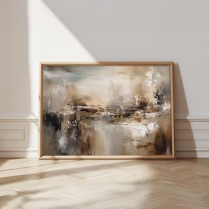 Könnte beinhalten: Abstrakte Landschaftsmalerei in einem Holzrahmen. Das Kunstwerk zeigt eine Mischung aus neutralen Tönen, darunter Beige, Braun und Weiß, mit strukturierten Pinselstrichen. Das Gemälde lehnt an einer weißen Wand, mit natürlichem Licht und Schatten.