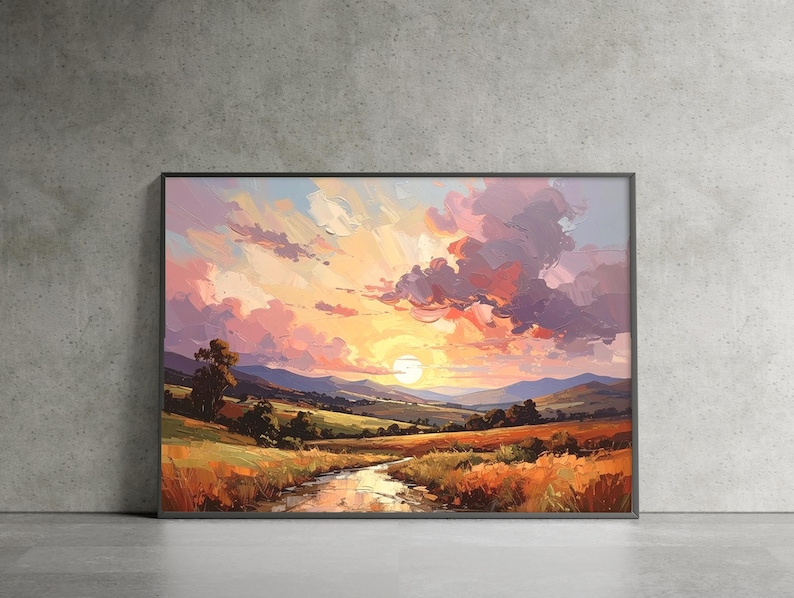 May include: Framed landscape painting depicting a sunset over a valley. The artwork features a vibrant sky with pink, orange, and purple hues. A river flows through the foreground, with fields and hills in the distance.