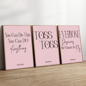 Könnte beinhalten: Drei gerahmte Kunstdrucke mit rosa Hintergründen und schwarzem Text. Die Drucke zeigen motivierende Sätze: "You Can Do This, You Can Do Anything", "TOSS TOSS" und "Everyone Deserves the Chance to Fly". The Good Witch ist unten aufgedruckt.