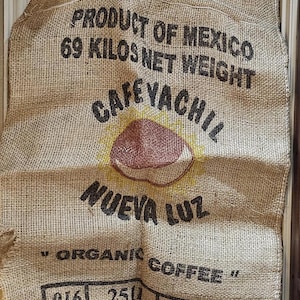 May include: A burlap coffee sack from Mexico, displaying the text "PRODUCT OF MEXICO" and "69 KILOS NET WEIGHT." The sack features the "CAFÉ YACHIL" logo and the words "NUEVA LUZ" and "ORGANIC COFFEE."