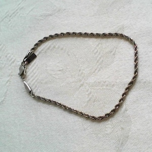 May include: A silver rope chain necklace with a clasp.