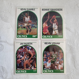 May include: Four vintage NBA Hoops basketball trading cards featuring Boston Celtics players. Cards include Kevin Gamble, Ronnie Grandison, Jim Paxson, and Kelvin Upshaw. Each card has a green arch design and the Celtics logo.