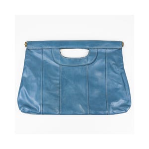 May include: A blue leather clutch bag featuring a rectangular shape with a built-in cutout handle at the top. The bag is constructed with vertical stitched panels and includes small metallic hardware accents at the top corners of the handle.