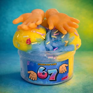 May include: A clear plastic container filled with blue and yellow slime, topped with two small orange plastic hands. The container has a label that reads "Stress Pop Slime" and the number "67". Sprinkles are scattered throughout the slime.