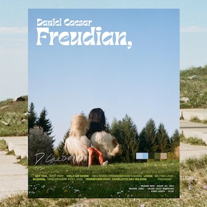 May include: Album cover art for Daniel Caesar's album "Freudian." The cover features a photograph of two people with their backs to the camera, sitting on a grassy hill. The sky is blue and the trees are green. The album title "Freudian" is written in white letters on a blue background.