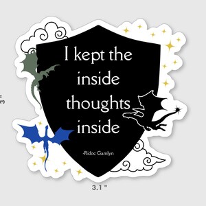 May include: A sticker with a black shield shape containing the text "I kept the inside thoughts inside" and the author's name. The sticker has a white border and features dragon illustrations in green, blue, and black, with gold star accents. The sticker is 3 inches by 3.1 inches.