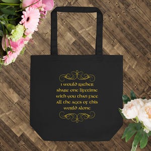 May include: Black tote bag with a gold quote that reads "I would rather share one lifetime with you than face all the ages of this world alone".