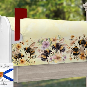 May include: A yellow mailbox cover with a watercolor design of bees and flowers. The bees are yellow and black with brown stripes. The flowers are pink, purple, and yellow. The cover is made of fabric and has a white border.
