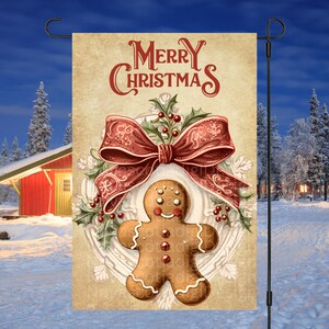 Peut inclure: Un drapeau de jardin de Noël de style vintage avec un bonhomme en pain d'épices au centre. Le bonhomme en pain d'épices est entouré d'une couronne avec un nœud rouge et du houx. Le texte "Merry Christmas" est en haut du drapeau.