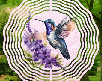 Puede incluir: Un molinillo de viento de metal rosa con un colibrí y flores moradas. El colibrí es azul, verde y rojo con un pico largo. Las flores son de estilo acuarela y tienen un fondo rosa.