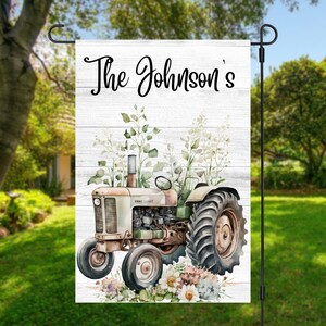 May include: A white wooden sign with the text "The Johnson's" in black cursive. A vintage green and white tractor with a floral design is in front of the sign.