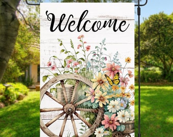 May include: A welcome garden flag with a whitewashed wood background. The flag features a vintage wagon wheel with a floral arrangement of pink, yellow, and white flowers. A yellow butterfly is perched on the flowers. The text "Welcome" is written in black cursive.