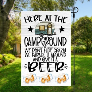 May include: A white garden flag with a cartoon camper van, stars, and the text "HERE AT THE CAMPGROUND WE DON'T HIDE CRAZY WE PARADE IT AROUND AND GIVE IT A BEER". There are four cartoon beer mugs with foam on top.