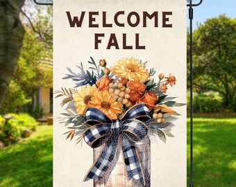 Op de afbeelding: Een herfst-welkoms tuin vlag met een aquarel illustratie van een boeket gele en oranje bloemen in een glazen pot met een blauw-wit geruit lint. De tekst "WELCOME FALL" is in bruine letters op de vlag gedrukt.