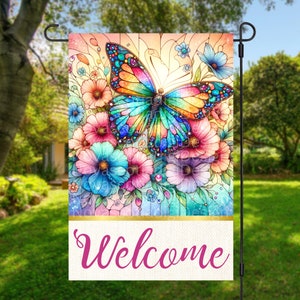May include: A colorful stained glass style butterfly garden flag with the word "Welcome" at the bottom. The butterfly is surrounded by flowers in shades of pink, blue, and purple.